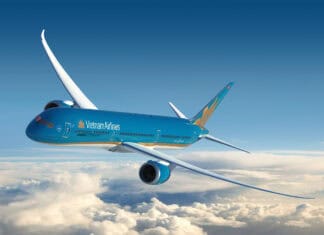 A Vietnam Airlines plane is soaring through a clear blue sky above white clouds, 2K Desktop Wallpaper