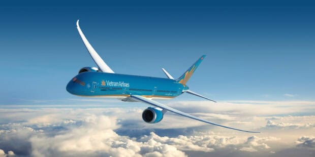 A Vietnam Airlines plane is soaring through a clear blue sky above white clouds, 2K Desktop Wallpaper
