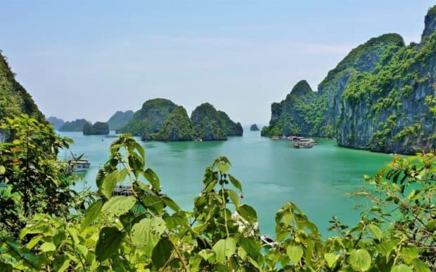 Vietnam Wallpapers show a serene bay with green islands and boats on calm water, HD Desktop Wallpaper