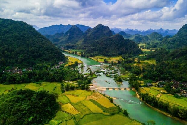 A scenic view of Vietnam Wallpapers showing a river flowing through green rice fields and hills, HD Desktop Wallpaper