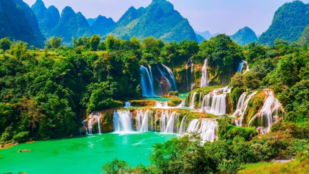 Vietnam Wallpapers showing lush green mountains and flowing waterfalls in a scenic view, 4K Desktop Wallpaper