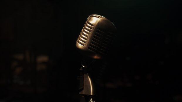 A close up of a vintage microphone glowing softly in a dark room with a dramatic atmosphere, 4K Desktop Wallpaper