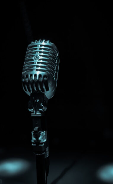 A vintage microphone stands in a dark room with a spotlight highlighting its metallic details, HD Mobile Wallpaper