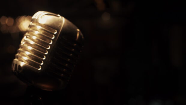 A vintage microphone shines with warm golden light in a dark background, 4K Desktop Wallpaper
