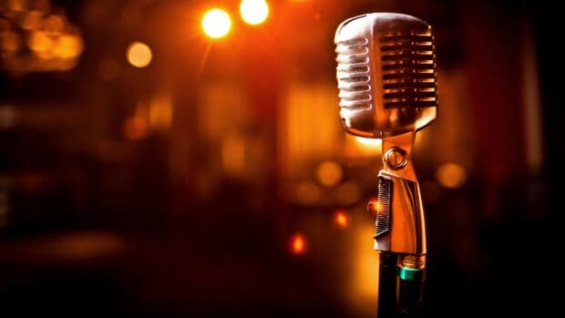 A close up of a vintage microphone glowing under warm stage lights, 4K Desktop Wallpaper