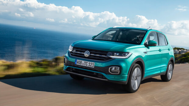 A green Volkswagen T Cross driving fast near the coast with a scenic ocean background, 4K Desktop Wallpaper