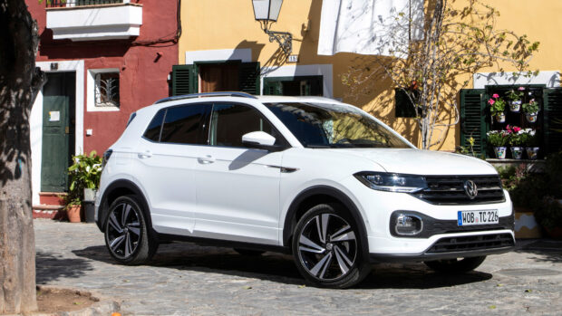 A white Volkswagen T Cross parked on a cobblestone street in front of colorful buildings, 4K Desktop Wallpaper