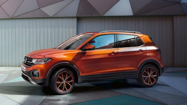 A bright orange Volkswagen T Cross parked beside a modern wall, HD Desktop Wallpaper