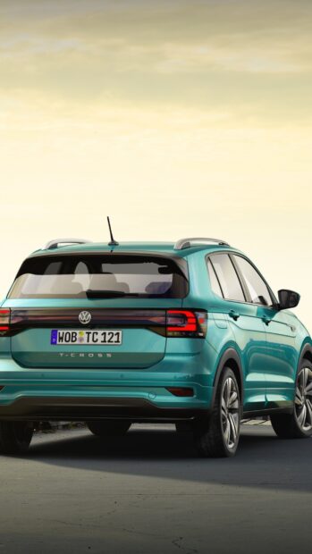 A turquoise Volkswagen T Cross is parked on a road under a soft sunset sky, showcasing its rear design and sporty features, 2K Mobile Wallpaper