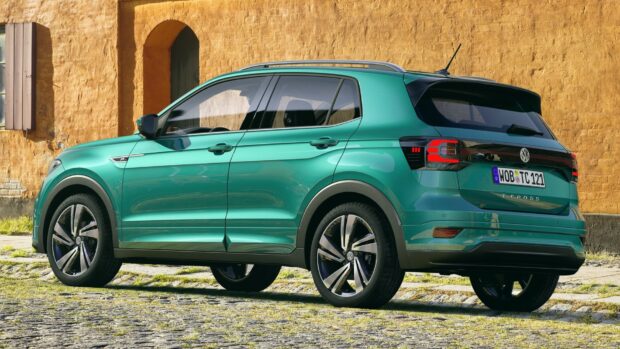 A green Volkswagen T Cross is parked on a cobblestone street with a yellow wall in the background, HD Desktop Wallpaper