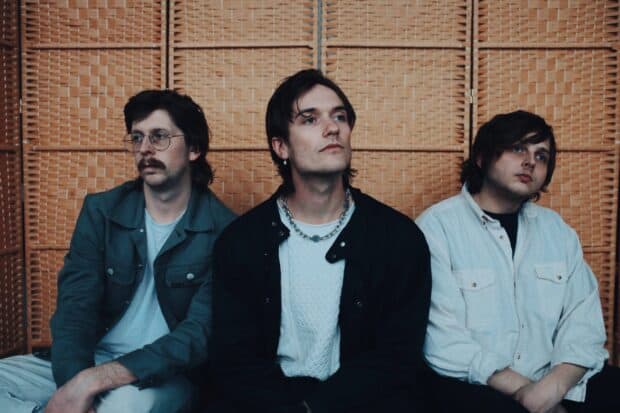 The Vundabar band members are sitting against a wicker background with thoughtful expressions, 2K Desktop Wallpaper