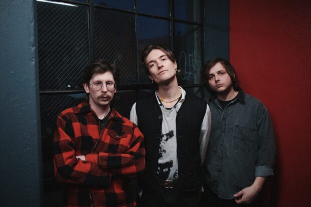 The Vundabar band members stand in front of a dark window and wall in a relaxed pose, 2K Desktop Wallpaper