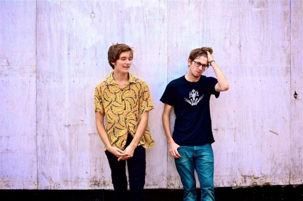 Two Vundabar band members stand against a wooden wall with relaxed poses, HD Desktop Wallpaper