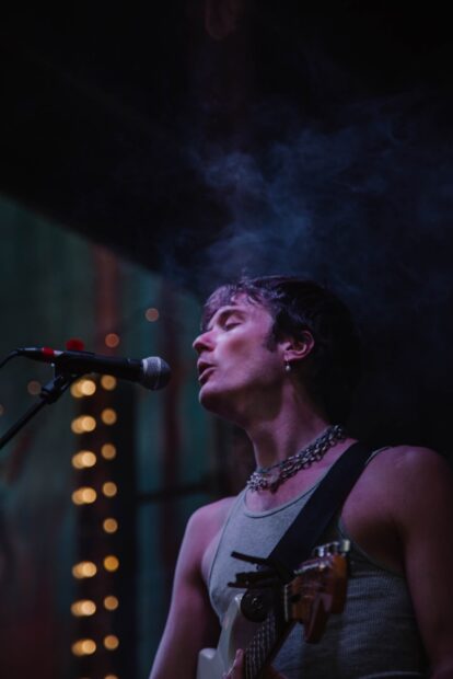 A member of Vundabar band sings intensely while playing guitar on stage, HD Mobile Wallpaper