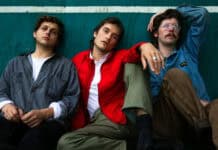 Three members of Vundabar band sitting against a green wall in casual clothes, 2K Desktop Wallpaper