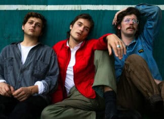 Three members of Vundabar band sitting against a green wall in casual clothes, 2K Desktop Wallpaper