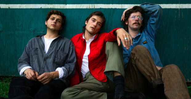 Three members of Vundabar band sitting against a green wall in casual clothes, 2K Desktop Wallpaper