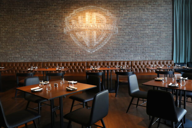 The Warner Bros logo is projected onto a brick wall above dining tables and chairs, HD Desktop Wallpaper