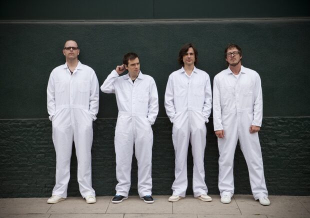 The Weezer band members are standing in white coveralls against a dark wall, HD Desktop Wallpaper