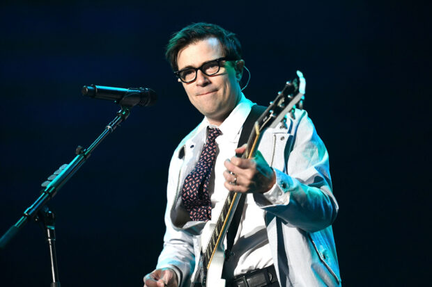 A close up of Weezer lead vocalist playing guitar during a live concert, 2K Desktop Wallpaper