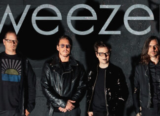 The Weezer band members standing together with a dark wall background, 2K Desktop Wallpaper