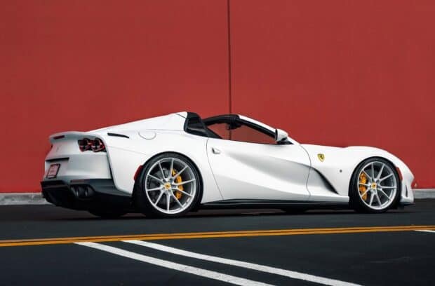 A white Ferrari 812 Gts is parked on the street next to a red wall in daylight, HD Desktop Wallpaper