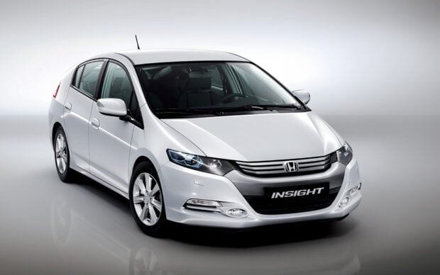 A white Honda Insight car is displayed in a well lit studio environment, showcasing its sleek design and front profile, HD Desktop Wallpaper