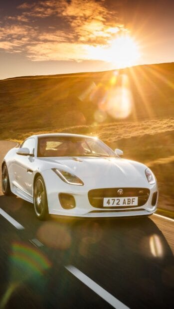 A white Jaguar F Type is driving on a winding road with sunlight shining brightly in the background, HD Phone Wallpaper