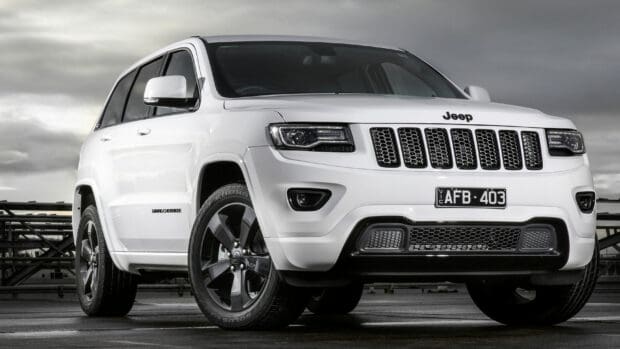 A white Jeep Grand Cherokee is parked on a wet ground under a cloudy sky, 2K Desktop Wallpaper