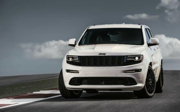 A white Jeep Grand Cherokee stands prominently on a race track under a cloudy sky, 2K Desktop Wallpaper
