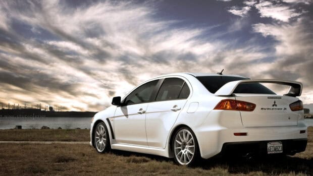 A white Lancer Evo car is parked on grass with a cloudy sky in the background, HD Desktop Wallpaper