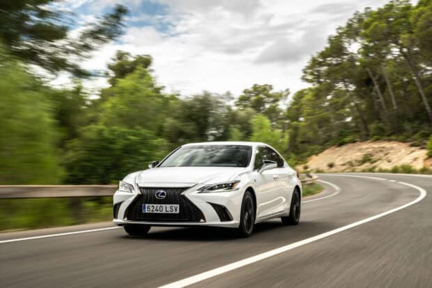 A white Lexus Es is driving fast on a curved road surrounded by green trees, 2K Desktop Wallpaper