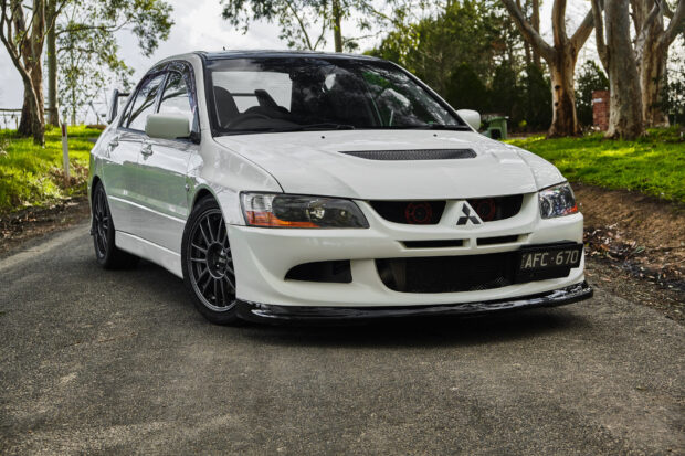 The Lancer Evo is parked on a road surrounded by trees and greenery, HD Desktop Wallpaper