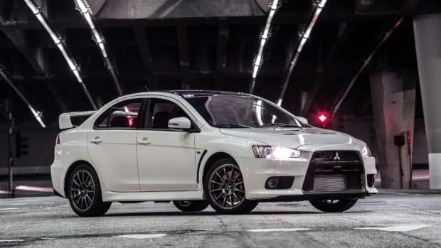 A white Mitsubishi Lancer Evo is parked under city lights with its headlights on, HD Desktop Wallpaper