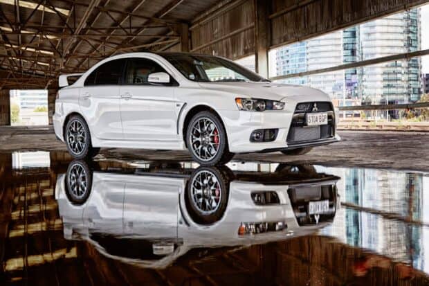 A white Mitsubishi Lancer Evo is parked inside a building with a clear reflection on the wet floor, HD Desktop Wallpaper