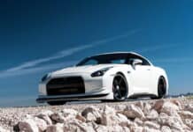 White Nissan GT R sports car is parked on rocky ground under a clear blue sky, 2K Desktop Wallpaper
