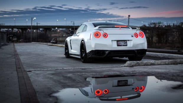 A Nissan GT R is parked near a bridge reflecting in a puddle, 4K Desktop Wallpaper