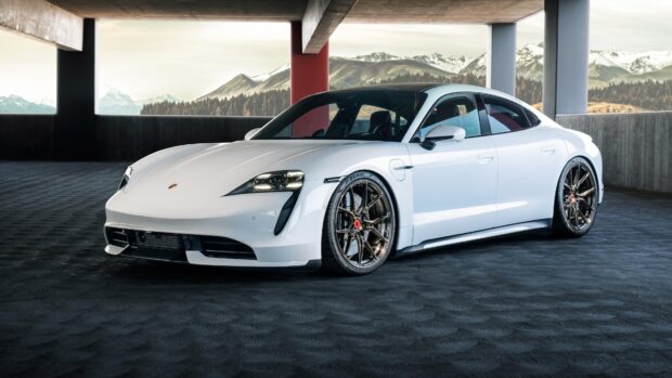 A white Porsche Taycan is parked in a modern garage with mountain views in the background, 4K Desktop Wallpaper