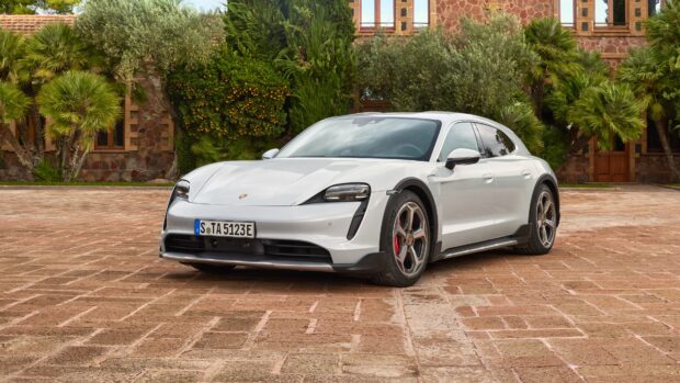 A white Porsche Taycan is parked in front of a stone building with greenery around, 4K Desktop Wallpaper
