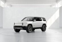 A white Rivian Automotive vehicle is shown inside a minimalist studio area with natural light, 2K Desktop Wallpaper