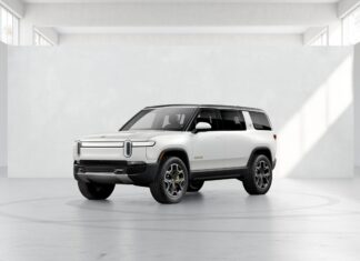A white Rivian Automotive vehicle is shown inside a minimalist studio area with natural light, 2K Desktop Wallpaper