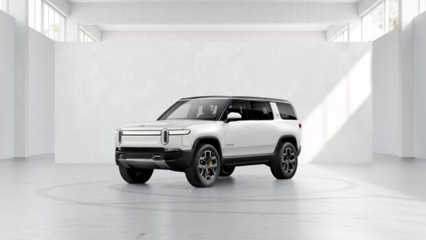 A white Rivian Automotive vehicle is shown inside a minimalist studio area with natural light, 2K Desktop Wallpaper
