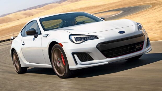 A white Subaru BRZ is shown speeding on a curved racetrack with dry hills in the background, HD Desktop Wallpaper