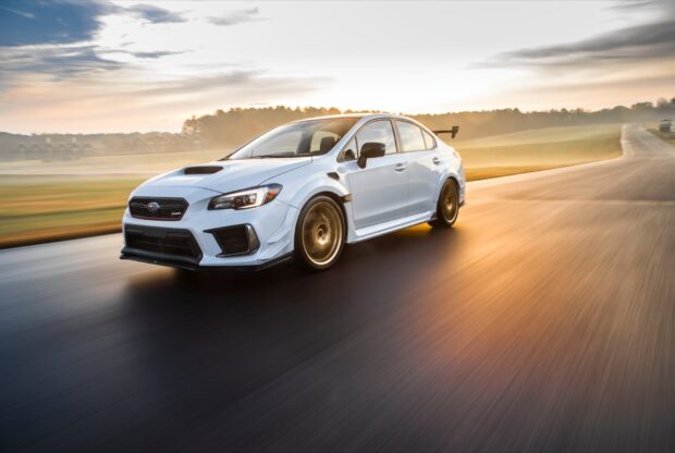 A white Subaru WRX is captured driving at high speed on a race track during sunset, HD Desktop Wallpaper
