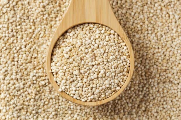 A close up of white quinoa grains filling a wooden spoon on a textured surface, HD Desktop Wallpaper