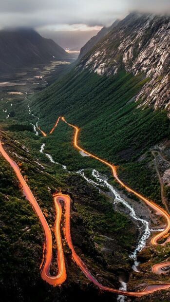 A winding mountain road illuminated at night runs through lush greenery in Norway, HD Phone Wallpaper