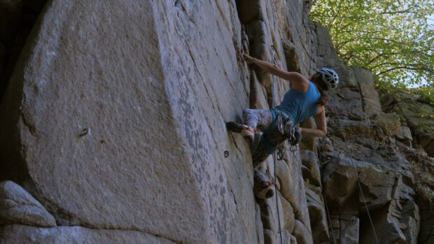 A woman wearing safety gear scales a large rocky cliff in an outdoor rock climbing activity, 4K Desktop Wallpaper
