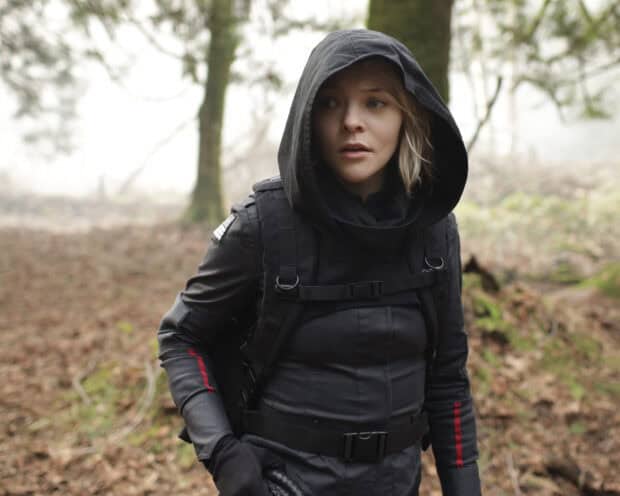 A woman wearing tactical gear and hooded jacket stands in a forest scene from Motherland Fort Salem, 2K Desktop Wallpaper