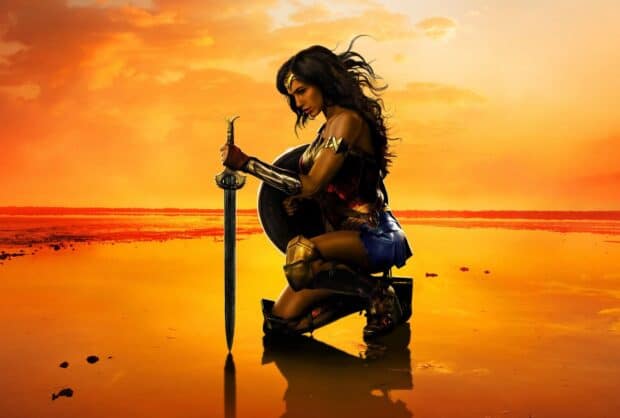 Wonder Woman is kneeling with a sword and shield during a golden sunset, 2K Desktop Wallpaper