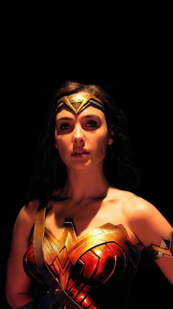Wonder Woman stands strong in her golden armor under dramatic lighting, 2K Mobile Wallpaper